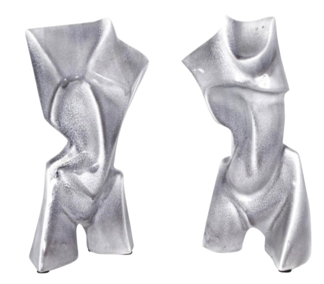 Pair of Ceramic Torso Sculptures: Pair of ceramic sculptures in speckled gray glaze having geometric, stylized figural form, sans head and lower limbs, with futurist influence. 15"H x 9"W x 5"D