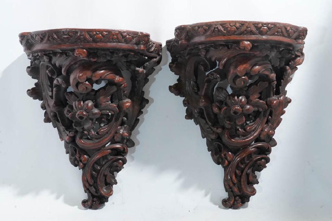 Pair Terra Cotta Wall Brackets: Modeled with a scrolled and foliage flowering motif. In a reddish brown finish. 13.5"H x 11"W