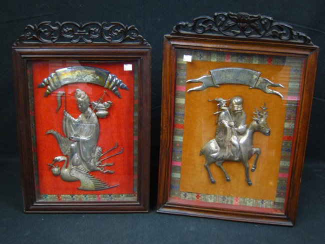 TWO CHINESE SILVER PLAQUES:: Two compatible and complimentary Chinese silver plaques depicting a male and female deities riding on mythological creatures. Each mounted in custom carved rosewood shadow box frames. 16" x 12"