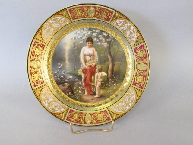 ROYAL VIENNA PLATE:: Depicting Venus and Cupid in the center, with raised gilt decoration to outer rim. Royal Vienna mark on underside, and numbered "22748". 8.75" in diameter.