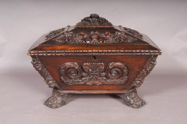 FINELY CARVED WINE CELLARETTE: Early 19th century sarcophagus form, resting on four feet. Original scroll and fruit applied carvings. Original lead liner. 24"H X 20.75"D X 31"W