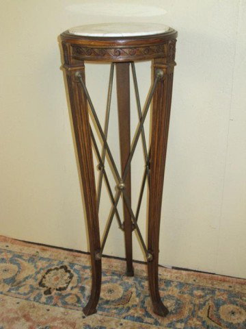 MARBLE TOP AND BRONZE PEDESTAL:: Having an inset circular white marble top over 3 tapering fluted legs connected by x-form brass bars. The apron with a carved undulating waves motif. 42.5"H X 14.5"W From a fine Connecticut home