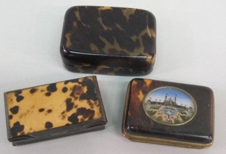 3 TORTOISESHELL BOXES:: A lidded pill box (Note: Crack). A hinged brass box with tortoiseshell inlaid lid. And a pill box lined with blue fabric and having a hand painted palace garden scene to lid. Boxes measure: 1" X 2" X 