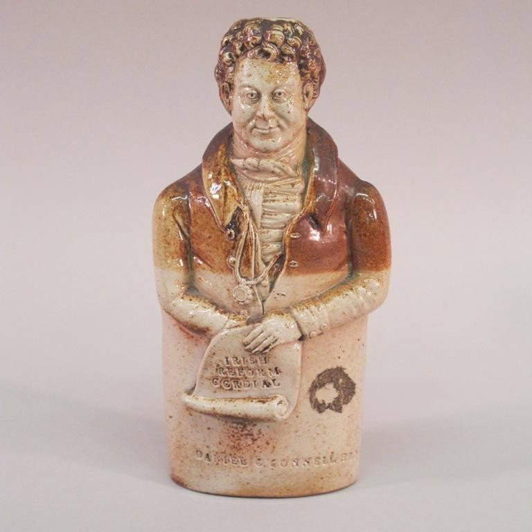 DENBY & CODNOR PARK CHARACTER LIQUOR BOTTLE:: The stoneware figure marked "Daniel O'Connell Esq." at base. Holding a scroll marked "Irish Reform Cordial". Bournes Potteries, Derbyshire. 8"H Provenance: The Ferst estate