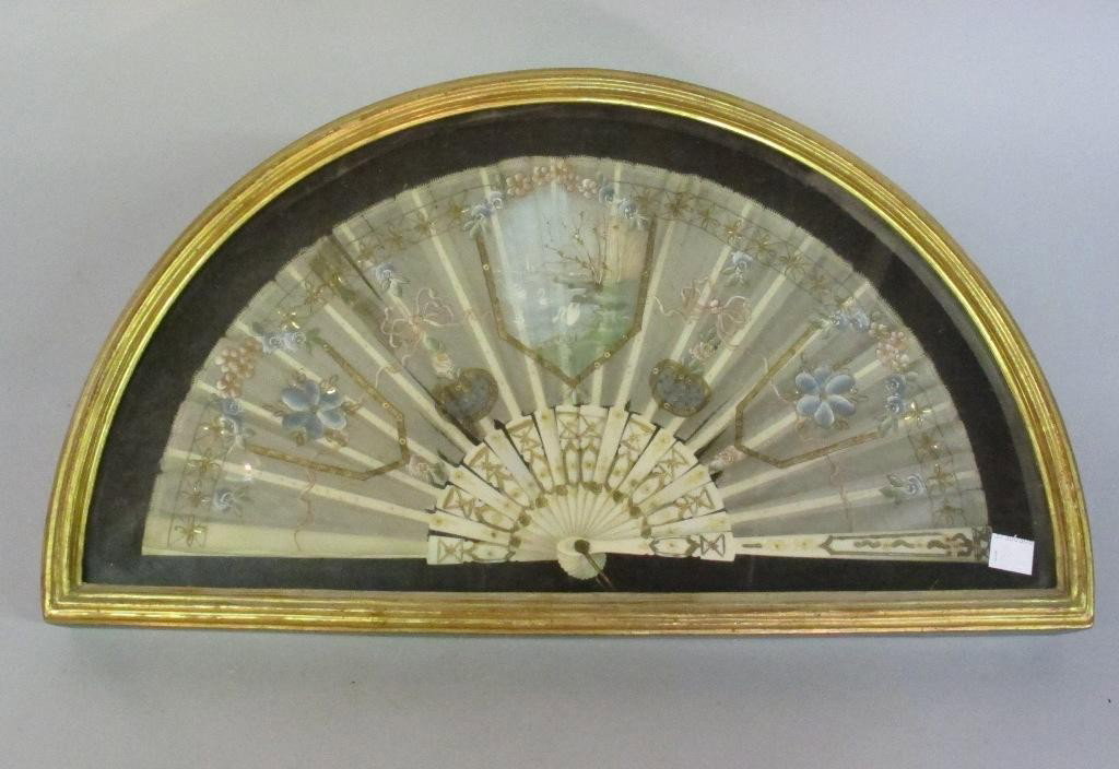 FRAMED FRENCH FAN:: A silk fan hand painted with swans, ribbons and flowers, and having a gilt accented ivory handle. Housed in a gilt demi lune shadow box. Provenance: The Ferst estate
