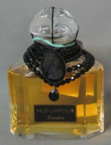 NUIT D'AMOUR BY GUERLAIN PERFUME:: A limited edition perfume by Guerlain in a signed Baccarat crystal flacon adorned with a Belle Époque collar of black beads and a black cameo medallion. Notes of lychee, pink berries, rose, jasmine,