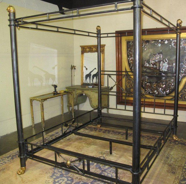 LARGE MAITLAND-SMITH WROUGHT IRON POSTER BED: A large hand made wrought iron poster bed painted black made by Maitland-Smith. Very heavy bed with a strong presence, each of the posts is adorned with brass lions head finials as well as brass claw