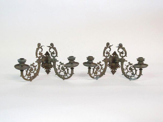 PAIR ANTIQUE BRONZE TWO-LIGHT SCONCES: Scrolling bronze two light candle sconces adorned with putti.