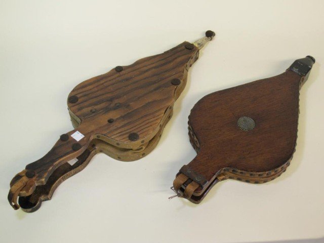 TWO ANTIQUE WOOD & LEATHER FIRE BELLOWS: A mahogany and brass studded leather bellow, and a carved pine and leather bellow with helmet and lion crest. 17"H and 23"H.