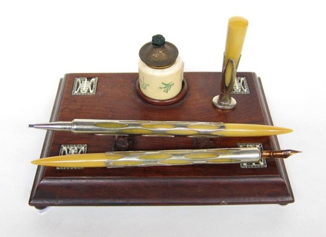 GROUP DESK TOP ITEMS:: A 3 piece silver overlay bakalite pen, graphite holder and seal along with an oriental wooden pen stand and ceramic ink pot.