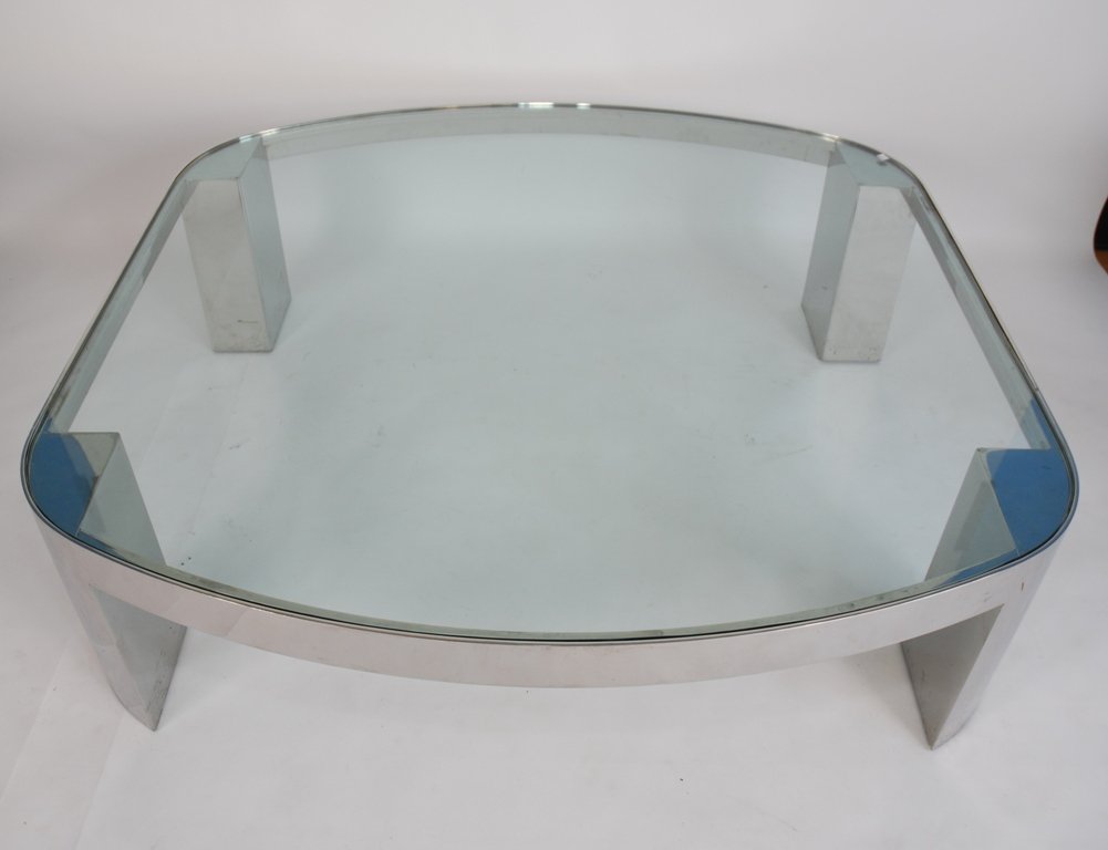 KARL SPRINGER POLISHED STEEL COFFEE TABLE: A square glass top surface with rounded corners, over a square polished steel base raised on four cylindrical steel legs. Good condition. 15.5"H X 45" X 45"