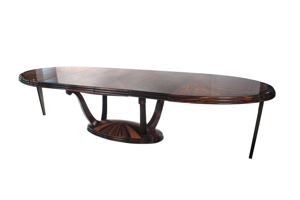 CONTEMPORARY ART DECO STYLE DINING TABLE:: A solid macassar ebony dining table with expanding oval top over an oval base connected by four scrolling legs. The surface in a radiating wood grain pattern. Accompanied with 4 leaves. Good condition