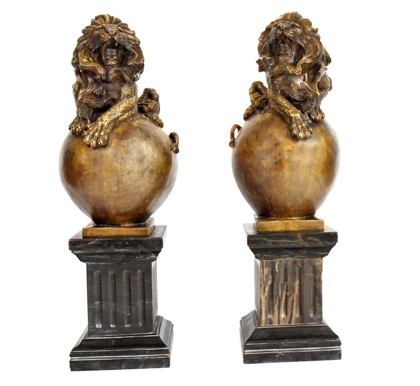 LARGE PAIR CAST BRONZE LION STATUES:: A pair of cast bronze lions resting on balls, each mounted on a black marble column. 39"H