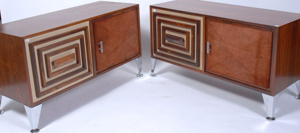 PAIR MID CENTURY MODERN CREDENZAS: Mahogany credenzas, each with two cabinet doors, one a suede covered convex diamond panel, the other with graduating wood frames surrounding the central door handle. Raised on tapering chrome bracket