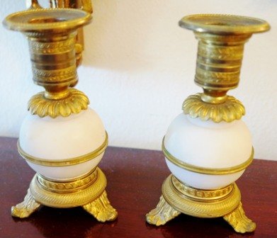 A PAIR OF GILT BRONZE AND ALABASTER CANDLESTICKS:: of baluster form having broad gilt bronze rims above the alabaster globe standards, raised on a circular foot ending in three splayed feet. Height 5 1/2 inches.