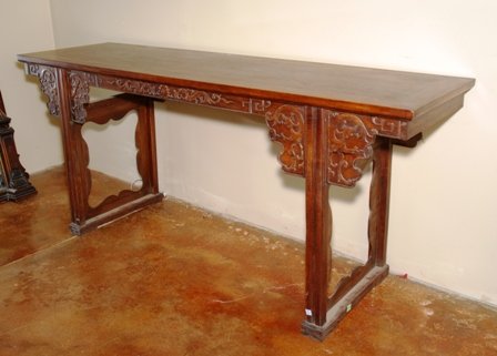 A CHINESE CARVED HUANGHUALI ALTAR TABLE:: 20th century, of substantial size, the rectangular top over the carved apron depicting dragons, the straight supports joined by carved shaped panels. Height 34 1/2 x width 78 7/8 x depth 23 inches.