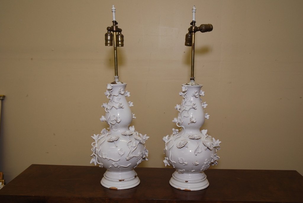 PAIR BLANC DE CHINE FLORAL TABLE LAMPS: Pair of white ceramic lamps with applied floral motif. Painted wood base. 31.25" to Finial top, Vase 17" without base Note: As is. Some minor loss. Repair to one lamp vase at top