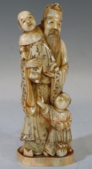 CARVED ASIAN IVORY FIGURE SCHOLAR WITH CHILDREN: Late 19th / Early 20th century. The fine ivory carving depicts a bearded scholar holding a child while another stands at his feet. Character marks to base. 8"H