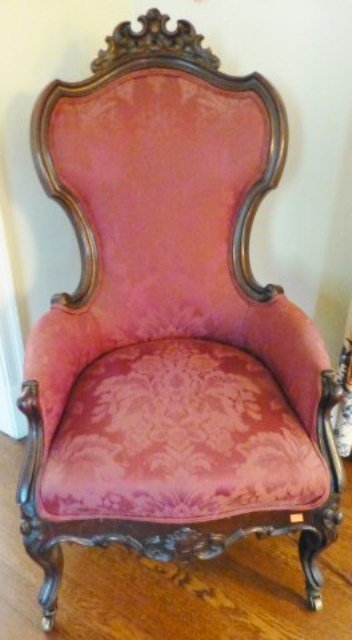 SLIPPER CHAIR: A Mid 19th Century American Victorian dark patinated carved walnut parlor slipper chair in burgundy Damask upholstery. The shield form back having a carved crest, above curved arms over a serpentine s