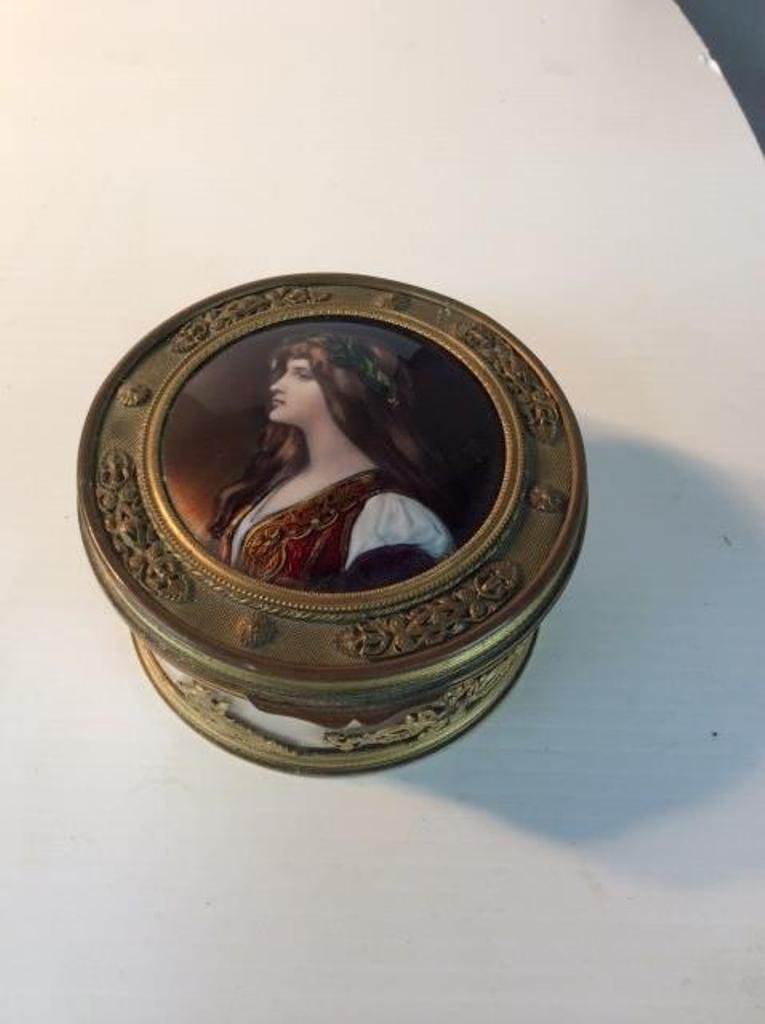 BRONZE CRYSTAL AND ENAMEL DRESSER BOX: The circular form crystal box having a bronze lid and applied decoration . The top having an inset enamel painted portrait of a classically dressed maiden. Monogrammed and numbered. 2 3/4"H X 4 3/4"Di