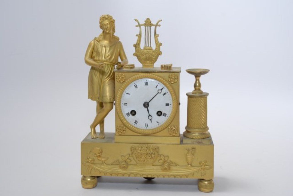 FRENCH GILT BRONZE MANTEL CLOCK: Porcelain face mantle clock depicting a lyre and figure. With pendulum. No back cover. No marks visible. 9 1/2"H X 7 1/8"W X 2 3/8"D Note: Loss to and minor damage to right hand of figure