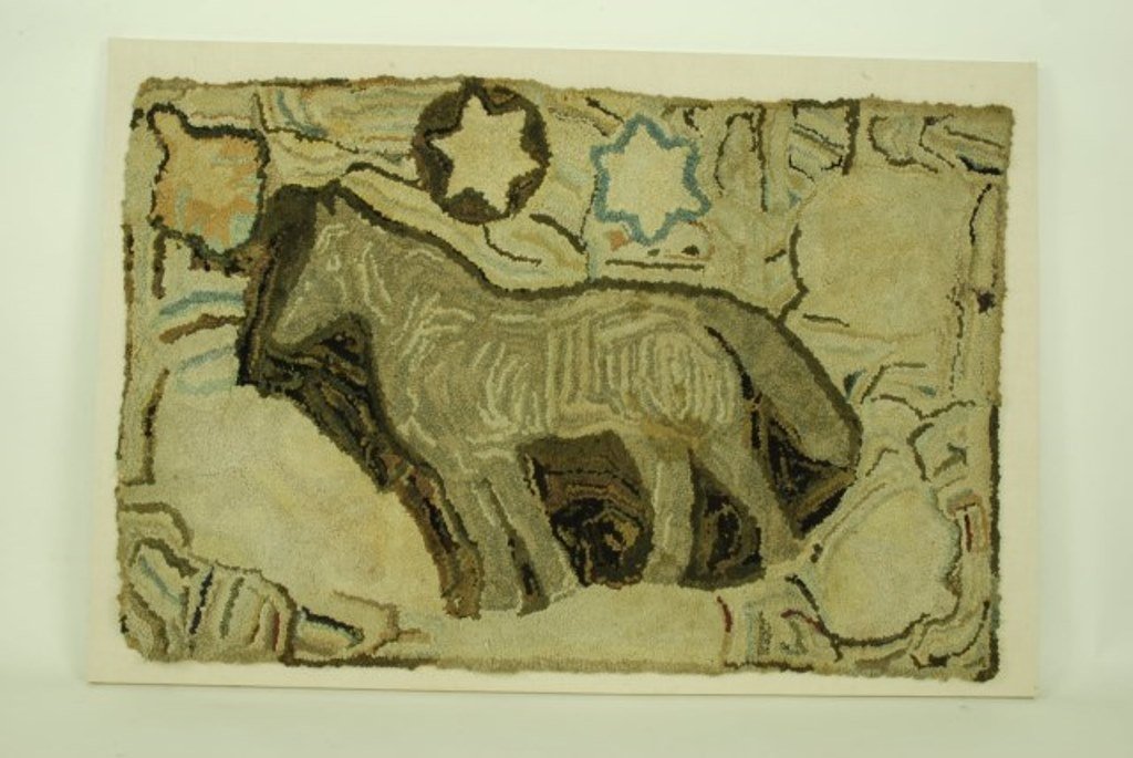 Antique Folk Art Hooked Rug: A early 20th Century wool hooked rug of New England origin depicting a horse beneath stars. Executed in brown, blue and cream tones. Mounted in a custom acrylic shadow box frame. 33"H X 55"W