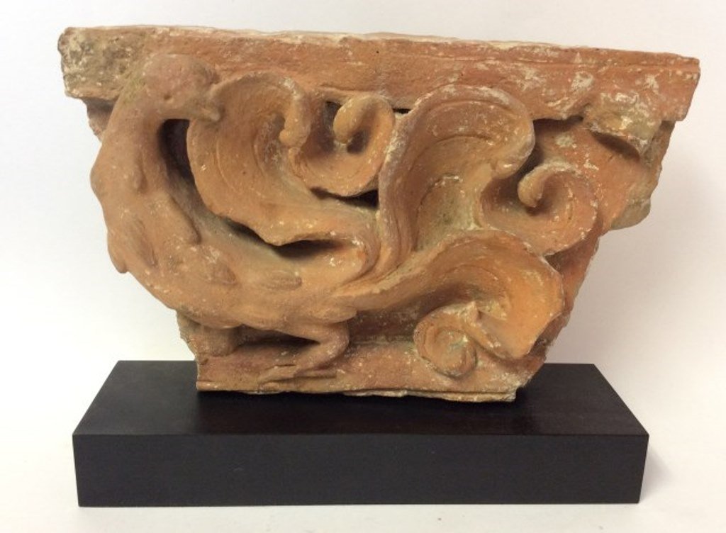 Indian Fragment: A large antique Indian unglazed pottery relief frieze fragment in a terracotta finish depicting a peacock. Mounted on a custom stand. Measures: 7¼" H X 2 1/2" W X12" L. Condition: Commensurate with a