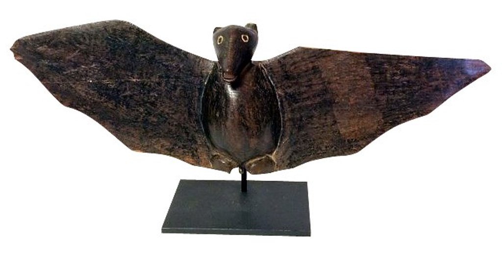 Maori Carved Bat: An antique Maori carved wooden figure depicting a bat with expanded wings. Mounted on a custom metal stand. Note: Minor losses to tips of ears and to wing. Measures: 15" L X 5½" H. Condition: Commens