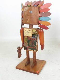 William Accorsi Sculpture Hatchet Indian Figure: Folk art figure of an Indian constructed from a cigar box, matches, and wood having painted feathers. Arms move and whole mounted to a board base. 27 inches height with base 10 inches width by 9 1/2 i
