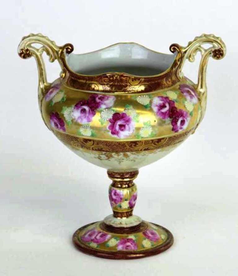 Nippon Parcel Gilt Painted Porcelain Compote: Nippon compote having handles in a scrolling foliage form and body painted and parcel gilt in a floral motif. In good condition. 10 inches height, 9.5 inches width, 7 inches depth. 10"H x 9.5"W x 7"D 