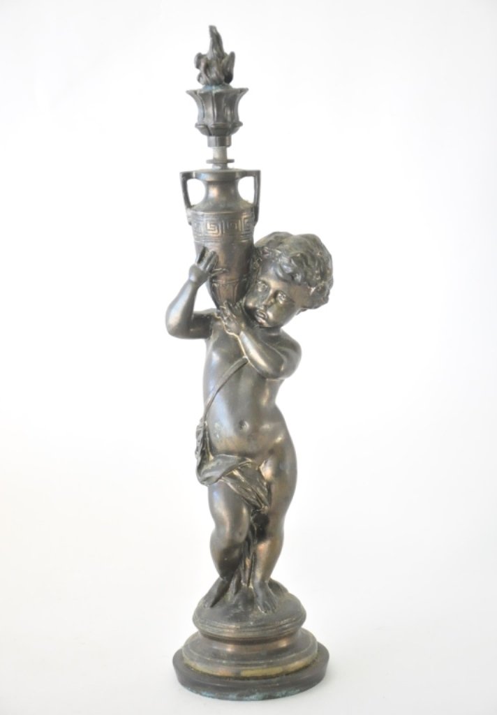 Sculpture of a Boy: Depicted partially clothed holding a flaming urn above his right shoulder, standing on a circular platform. White metal with bronze finish16.5 inches height, 4 inches diameter. 16.5"H x 4"Dia