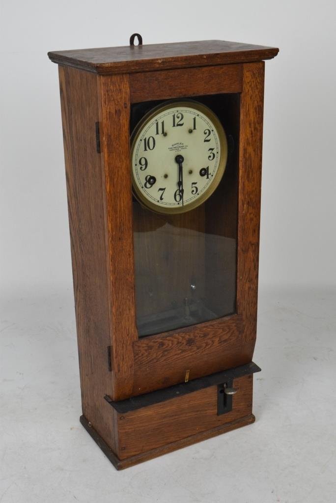 Simplex Time Recorder Clock: Oak framed time clock with glass front door over lever to start clock at base. Clock face reading "Simplex / Time Recorder Co., / Gardner Mass., / U.S.A." Measures 31 inches height, 14 inches width, 8