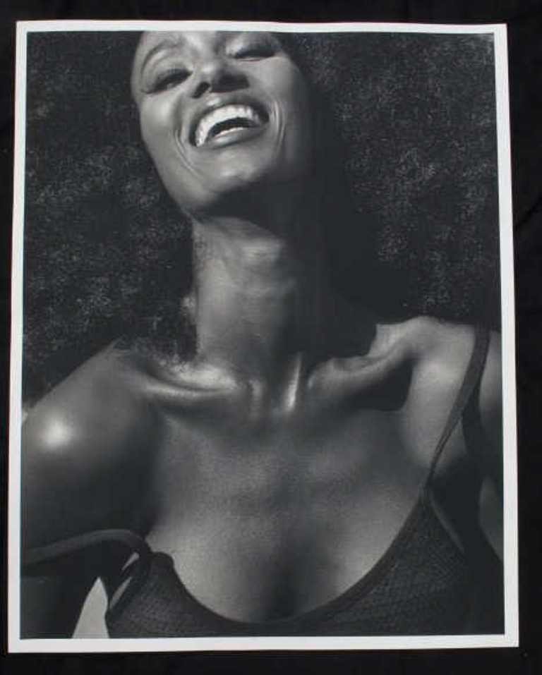 Michel Comte Photographic Print of Iman: Black and white photographic print on baryta paper by acclaimed Swiss photographer Michel Comte. Depicting a bust portrait of supermodel Iman laughing. Artist's mark in pencil to verso. 20 inches heig
