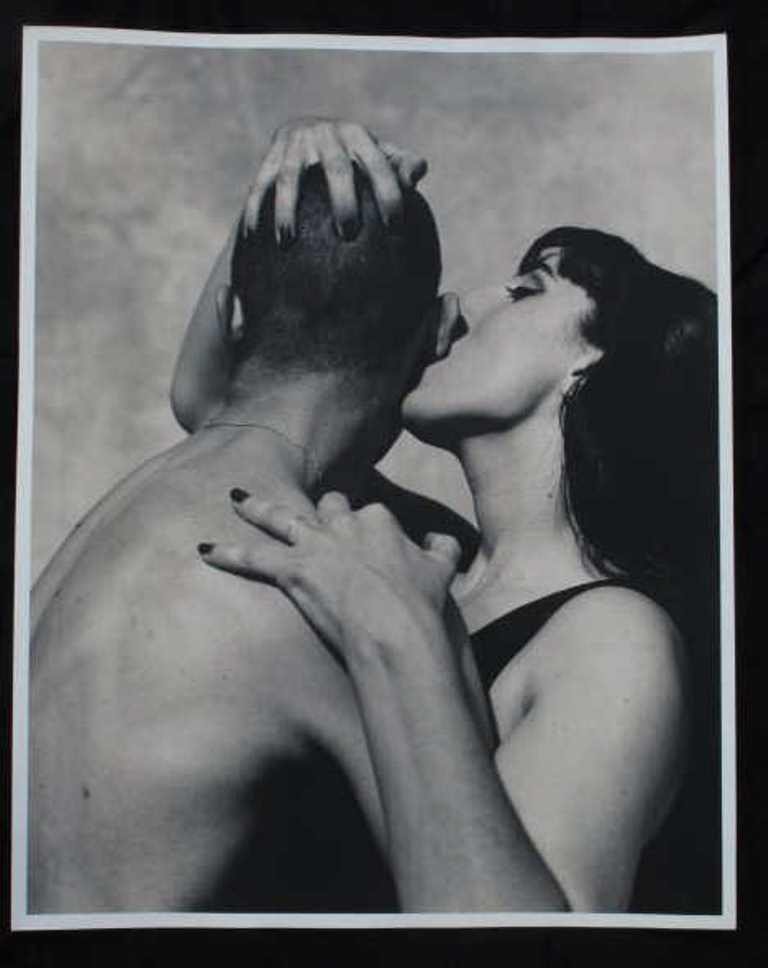 Michel Comte Photographic Print of Couple: Black and white photographic print on baryta paper by Swiss photgrapher Michel Comte. Depicting a woman kissing the side of man's head. Artist's pencil marks to verso. 20 inches height and 16 inches w