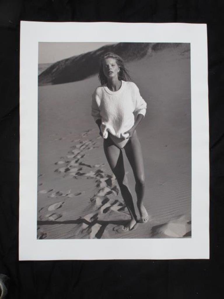 Michel Comte Photographic Print: Black and white photographic print on baryta paper by photographer Michel Comte. Depicting a woman wearing a sweater walking through a landscape of sand dunes. Artist's marks in pencil and stamp to ve