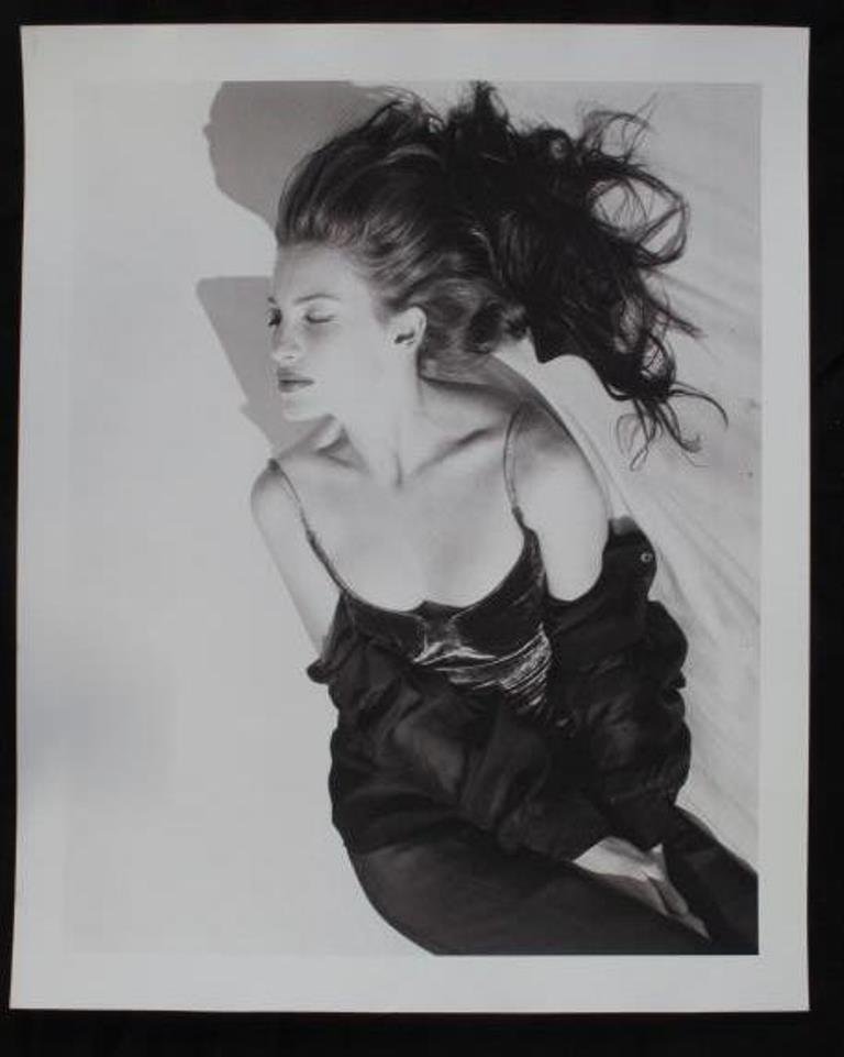 Baryta Print by Michel Comte: Black and white photographic print on baryta paper by Michel Comte. Depicting a female model laying on her back on a white background. Artist's marks in pencil and stamp to verso. 20 inches height and
