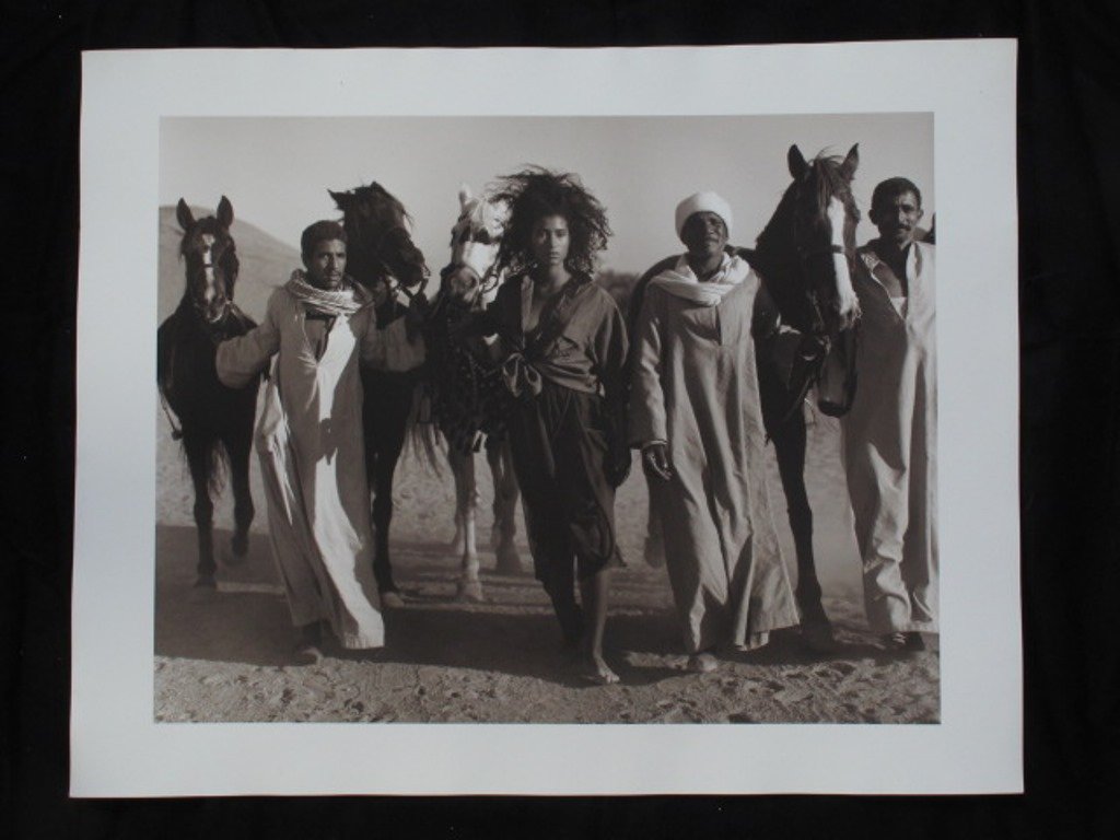 Michel Comte (1954-) Fashion Print: Black and white photographic print on baryta paper by Michel Comte. Depicting a female model with a group of nomadic men and horses in a desert landscape. Artist's marks in pencil and stamp to verso.