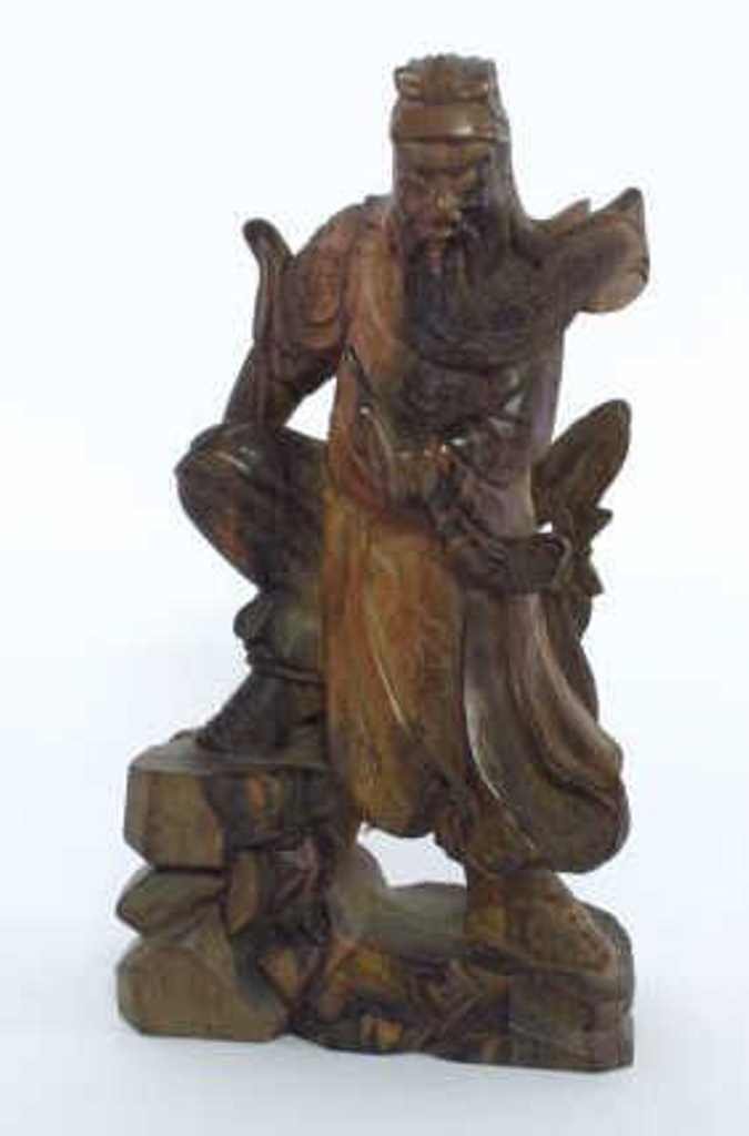 Oriental Carved Wood Statue: Carved wood Chinese statue. Depicting a male warrior figure with long beard and sword and holding a detachable spear while standing on a rocky crag. Carved with accent patterns throughout. 11 inches h