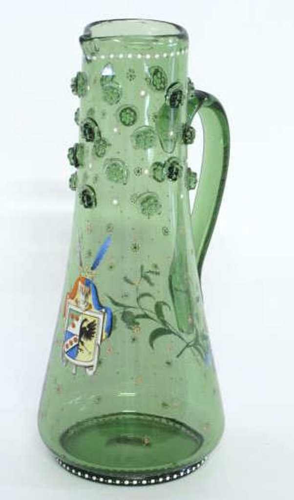 Moser Armorial Enameled Glass Pitcher: Green tinted Bohemian glass pitcher by Moser. Having dotted enamel pattern in white, red, and yellow throughout with a painted coat of arms to front and floral detail to back. Decorated with beaded pr