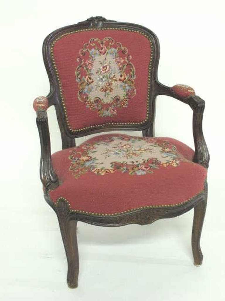 Floral Needlepoint Fauteuil: Fauteuil chair having rose pink needlepoint upholstery with floral motif and brass stud detail to cushion seat, arms, and back. Carved floral accents to frame on top, back, and skirt. 33 inches height