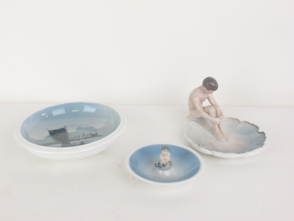 Group of Three Royal Copenhagen Grondahl: B&G Bing Grondahl Royal Copenhagen Nude Boy Water Lily Pad Figurine Dish, Sailing boat deep dish, and small nude figure dish various sizes no chips, cracks or repairs Dimensions: various sizes
