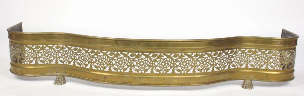Brass Fireplace Fender: Brass fireplace fender with four molded paw feet. Curved in form with reticulated foliate motif to side. 8.5 inches height, 48 inches width, 10 inches depth. 8.5"H x 48"W x 10"D Dimension: 8.5"H x 48"