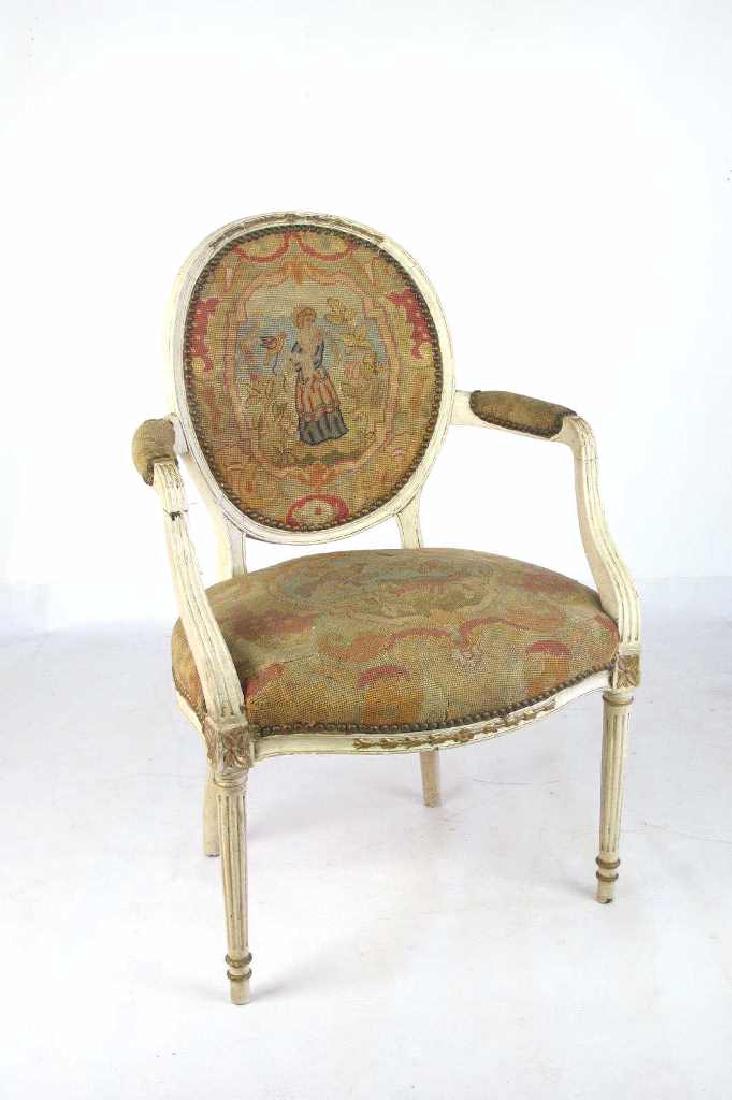 Needlepoint Fauteuil: Fauteuil having needlepoint upholstery to back, seat, and arms with stud detail. Vignette of female figure to back and birds to seat. White wood frame with fluted arms and legs. 37 inches height, 23.5