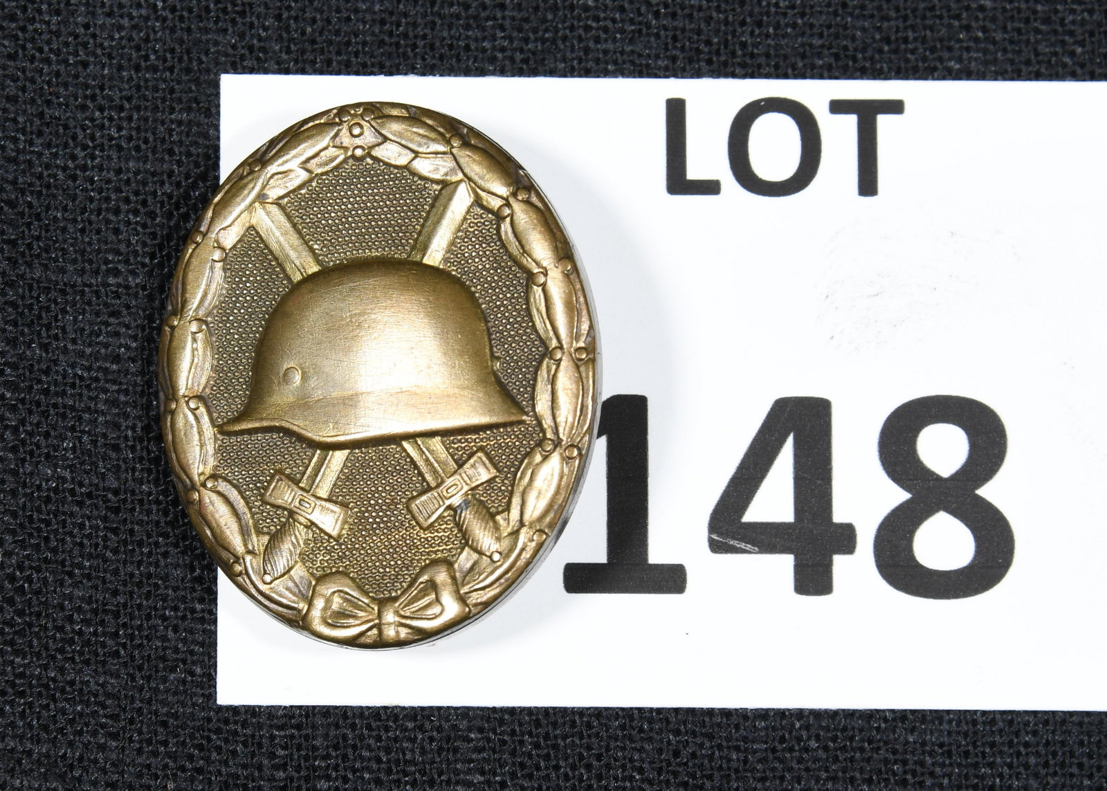 WWI German 1st Class Wound Badge: A WWI German 1st class wound badge in gold finish. This badge features an oval oak leaf wreath with helmet and two crossed swords at the center. Marked "30" on the reverse side. *notes- light wear and