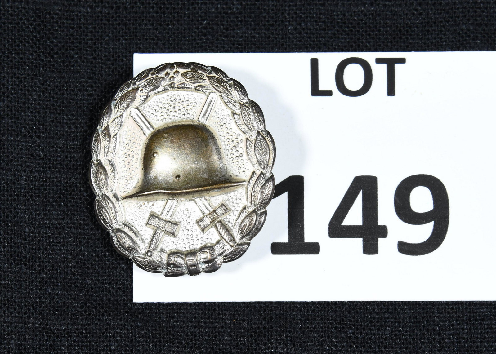 WWI German 2nd Class Wound Badge: A WWI German wound badge with silver finish for 2nd class. Given to members of the German military who had been wounded at least 3-4 times. This badge features an oak leaf wreath border with a helmet 