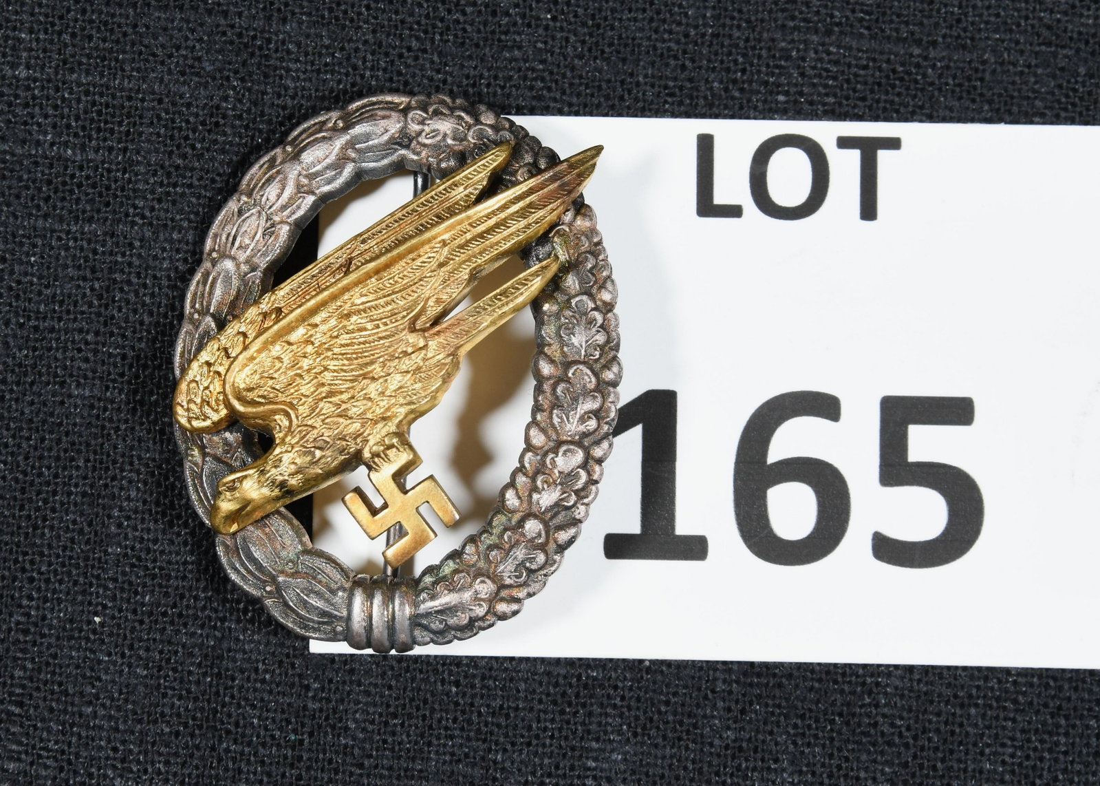 WWII Era Nazi Germany Paratrooper Badge: A WWII era Nazi Germany paratrooper badge. Badge consists of an oak leaf wreath with a flying eagle holding a swastika at the center. The reverse is marked with an "A". *notes- some tarnishing and gen
