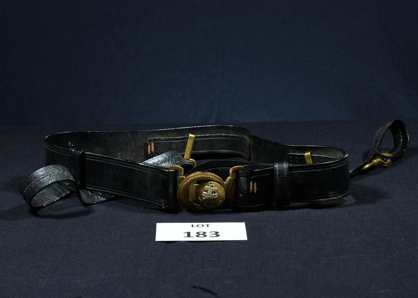 WWII Japanese Officer's Sword Belt: A WWII era Japanese officer's sword belt. Black leather belt with brass buckle and clips. Brass buckle features an Imperial Navy Anchor with a flower at the center. Belt measures 32" long.