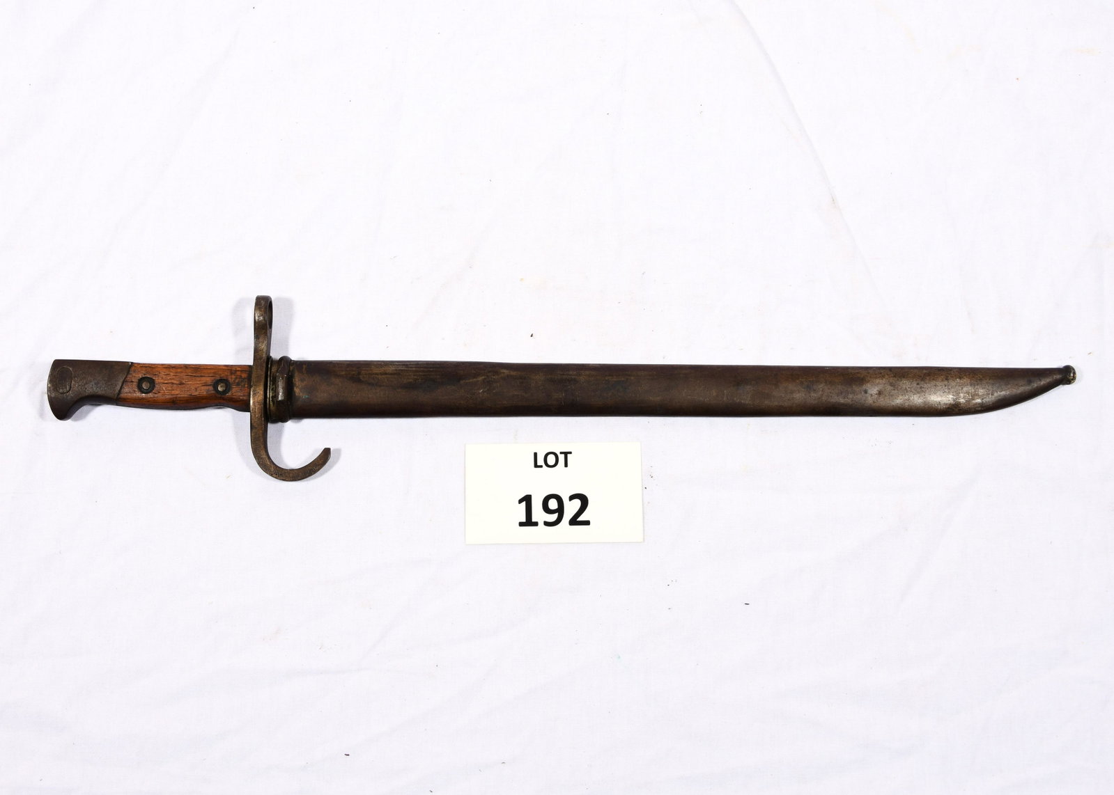 Bayonet and Scabbard: A bayonet with wooden grip and steel blade. Presented in a steel scabbard. 20 1/2" long. *notes- general wear and patina from age and use. Dents in scabbard.