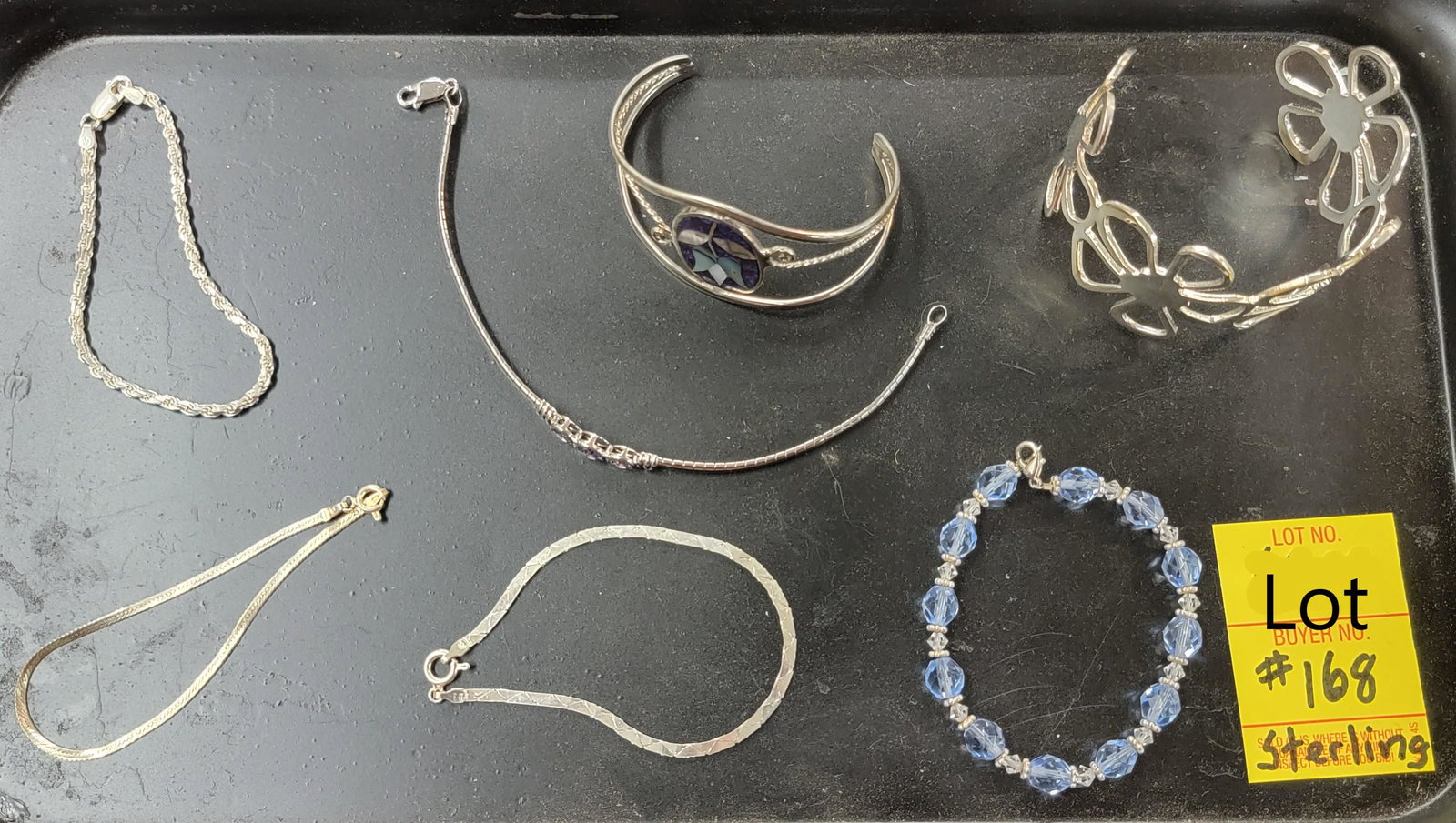Sterling Silver Bracelet Lot: A lot of seven sterling silver bracelets. Includes two flower themed cuffs, one with a mother of pearl tulip. Also featured are 3 chain bracelets, a bracelet with light blue beads and a three stoned a