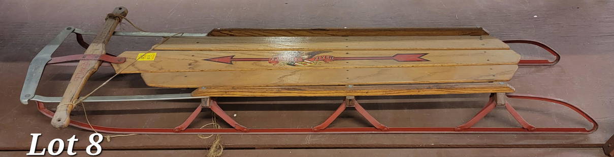 Antique Flexible Flyer Model F060 Sled: An antique Flexible Flyer Model F060 sled. This sled has a red painted metal frame, a wood seat with original graphics and a chrome front steering plank. Back of wood is marked "Model F060 from